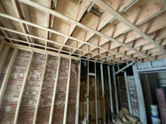 Property rehab with exposed brick, ceiling framing, and rough carpentry in progress