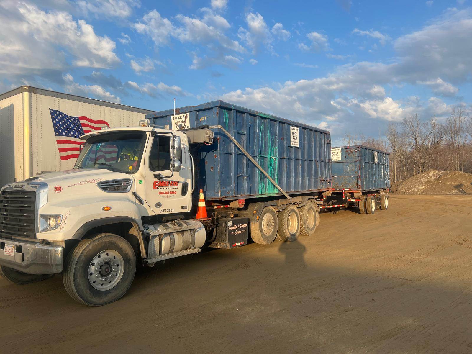 Roll-off dumpster truck hauling a second dumpster for larger property cleanout work